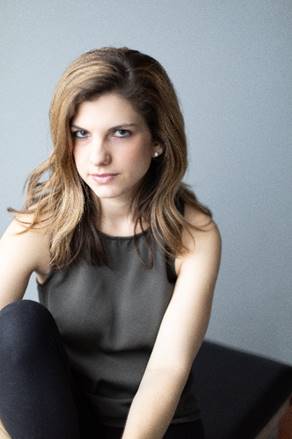 Author Julia Fine, woman with long brown hair in a sleeveless grey shirt giving the camera a dark look